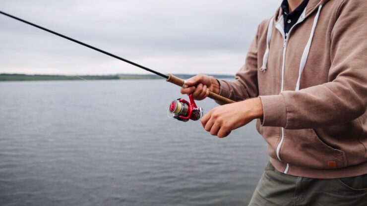 close-up-man-s-hand-holding-fishing-rod-near-lake